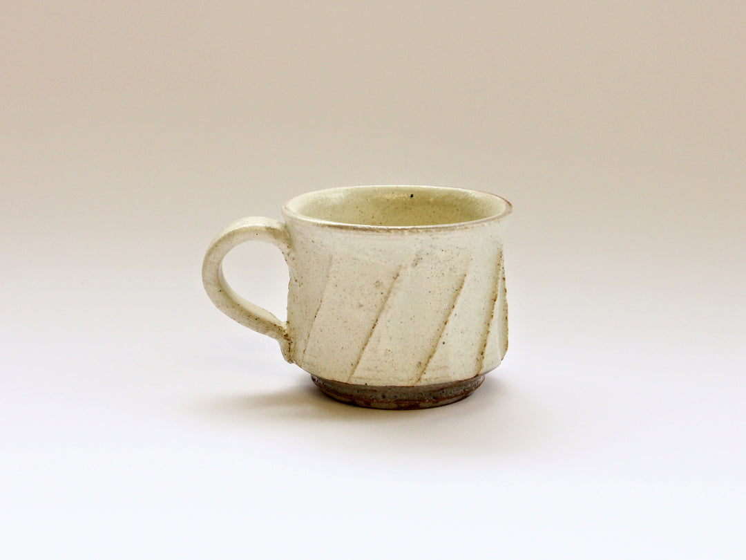 A white slip coffee cup with a carved matte surface